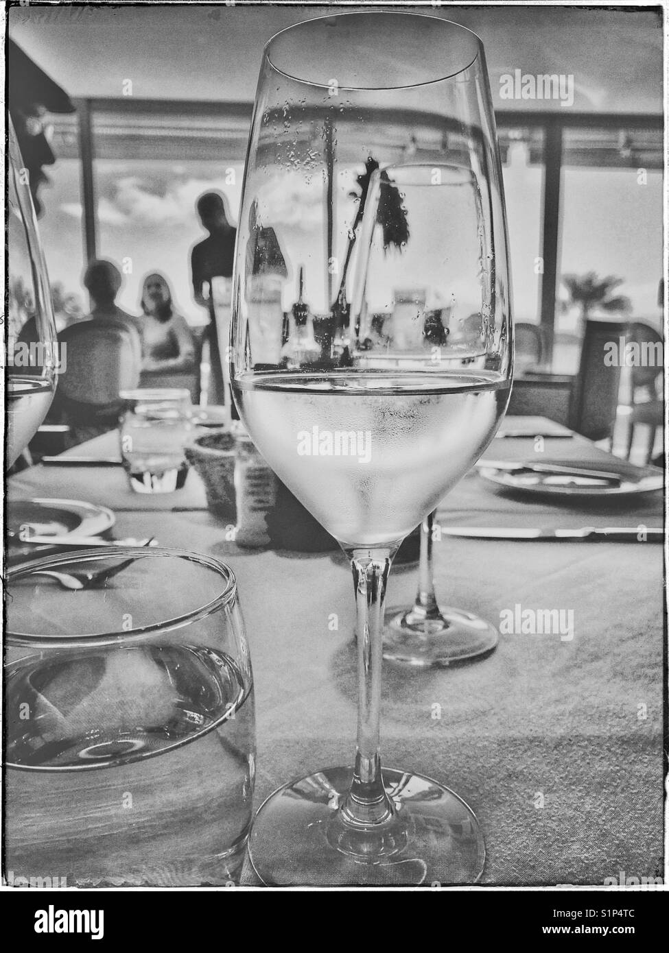 Black and white photo of white wine glass on restaurant table. - Smartphone Captured Stock Image