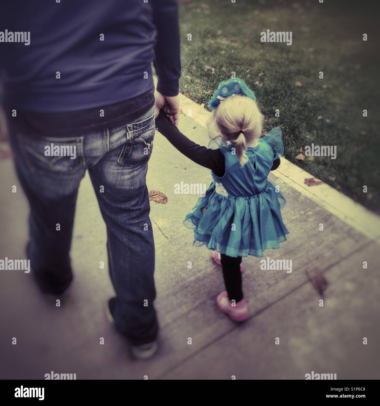 Father and daughter hold hands while trick or treating - Smartphone Captured Stock Image