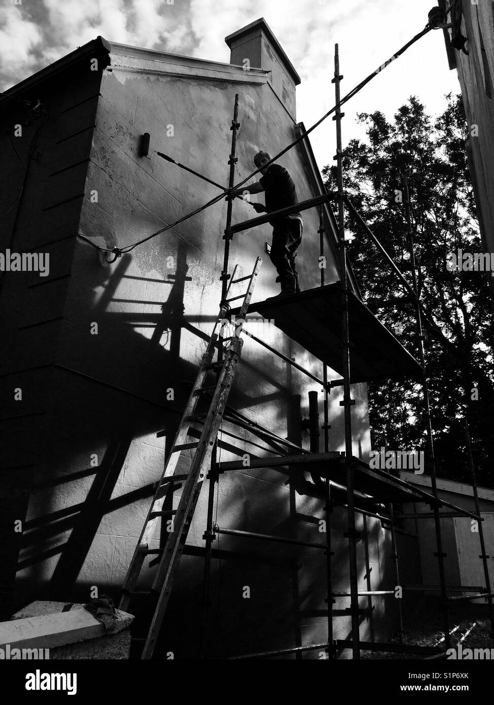 Man painting house on scaffolding - Smartphone Captured Stock Image