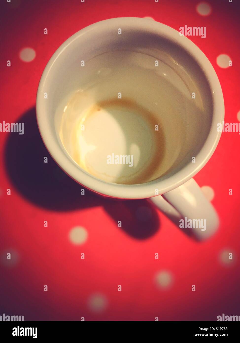 Empty coffee mug on red tablecloth with white dots - Smartphone Captured Stock Image