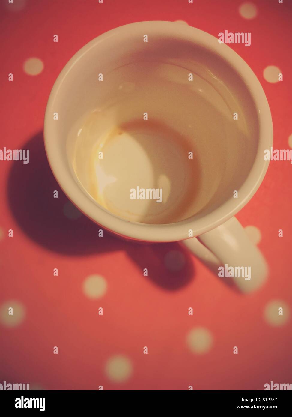 Empty coffee mug on red tablecloth with white dots - Smartphone Captured Stock Image