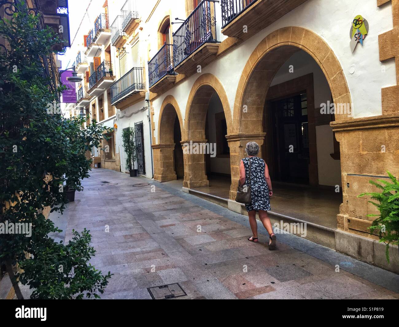 Woman walking down Calle Major, the pedestrianised main street in the Old Town of Javea, Alicante Province , Spain - Smartphone Captured Stock Image
