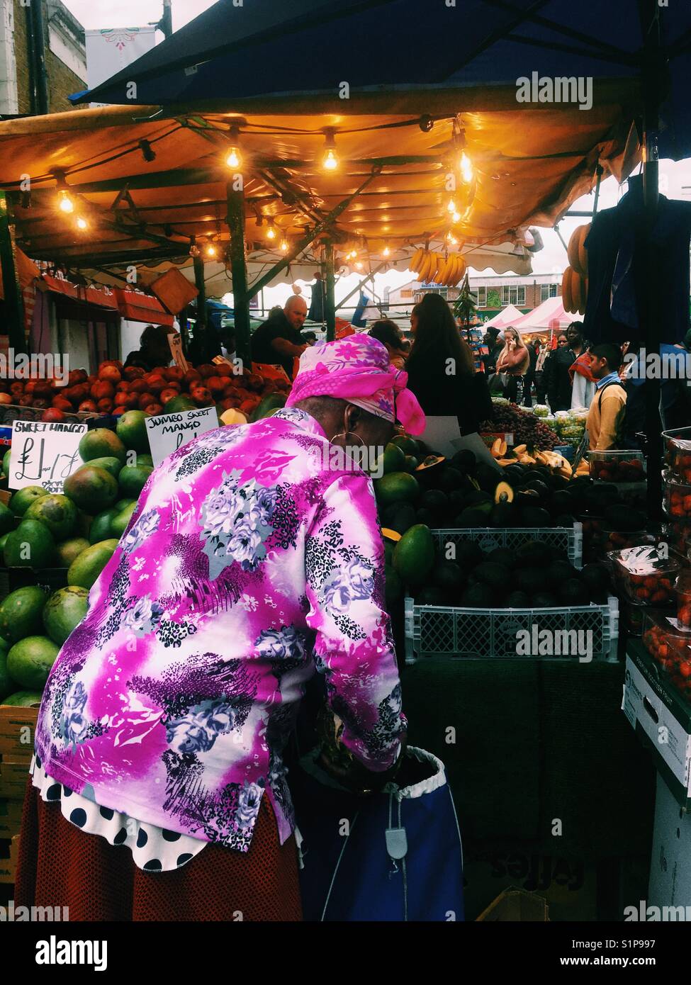 Lady in a colourful outfit shops at local street market at Ridley road London UK 30/09/2017 - Smartphone Captured Stock Image