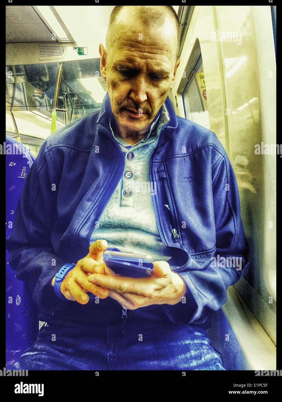 Middle aged Scandinavian man using a smartphone on the train, Sweden - Smartphone Captured Stock Image