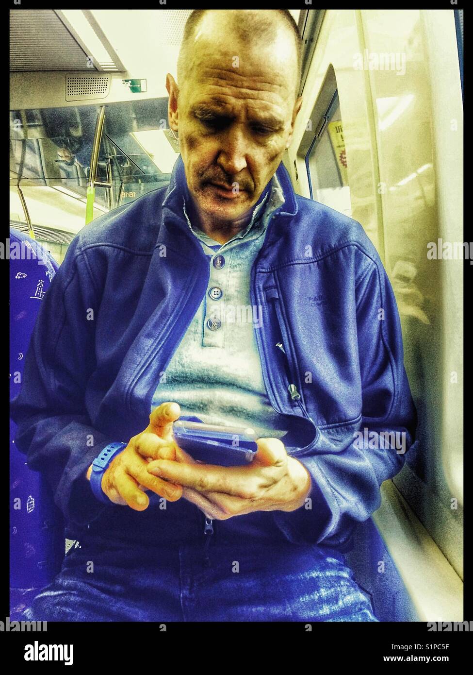 Middle aged Scandinavian man using a smartphone on the train, Sweden Stock Photo