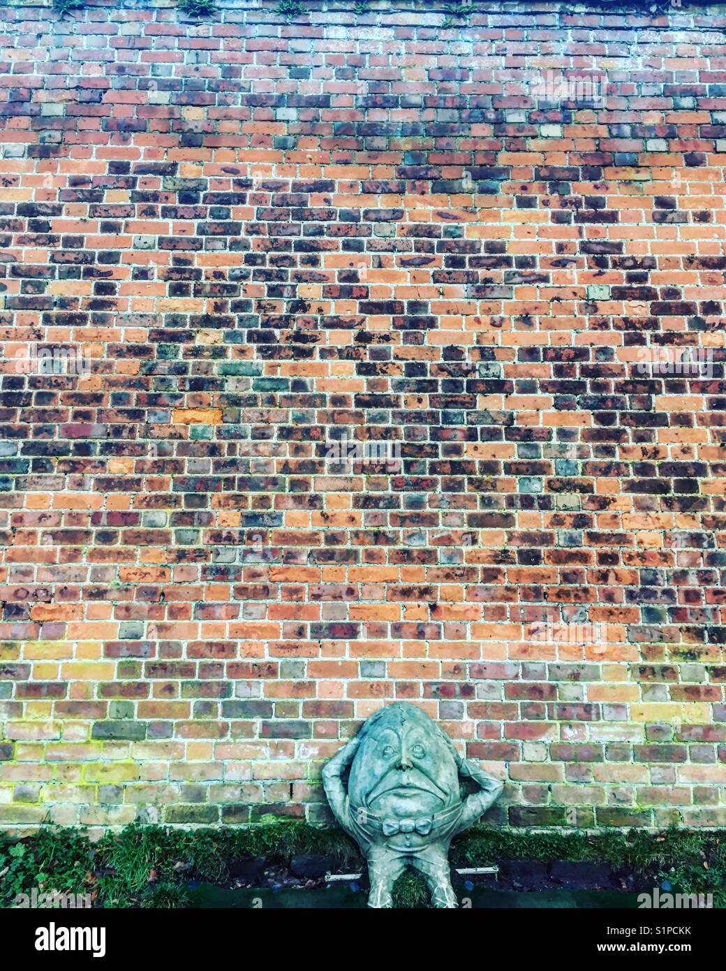 Humpty Dumpty sculpture in front of a colourful brick wall Stock Photo