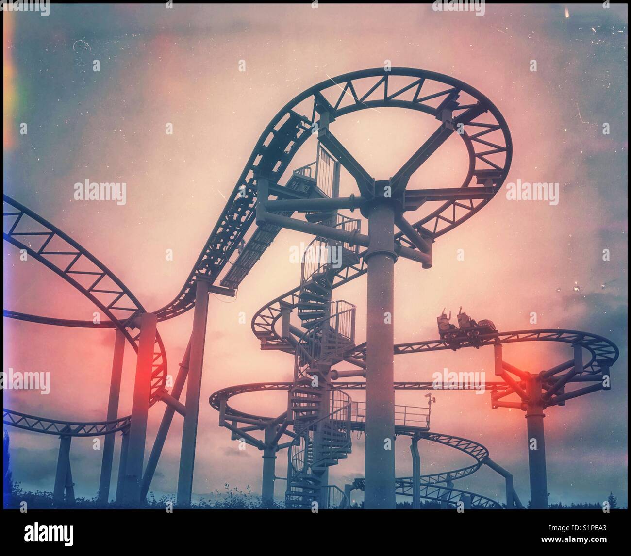 Three children wave their hands in the air as they enjoy an adrenaline infused rollercoaster ride at an amusement park. An image with a grunge effect image & simulated light fogging. © C.H. - Smartphone Captured Stock Image