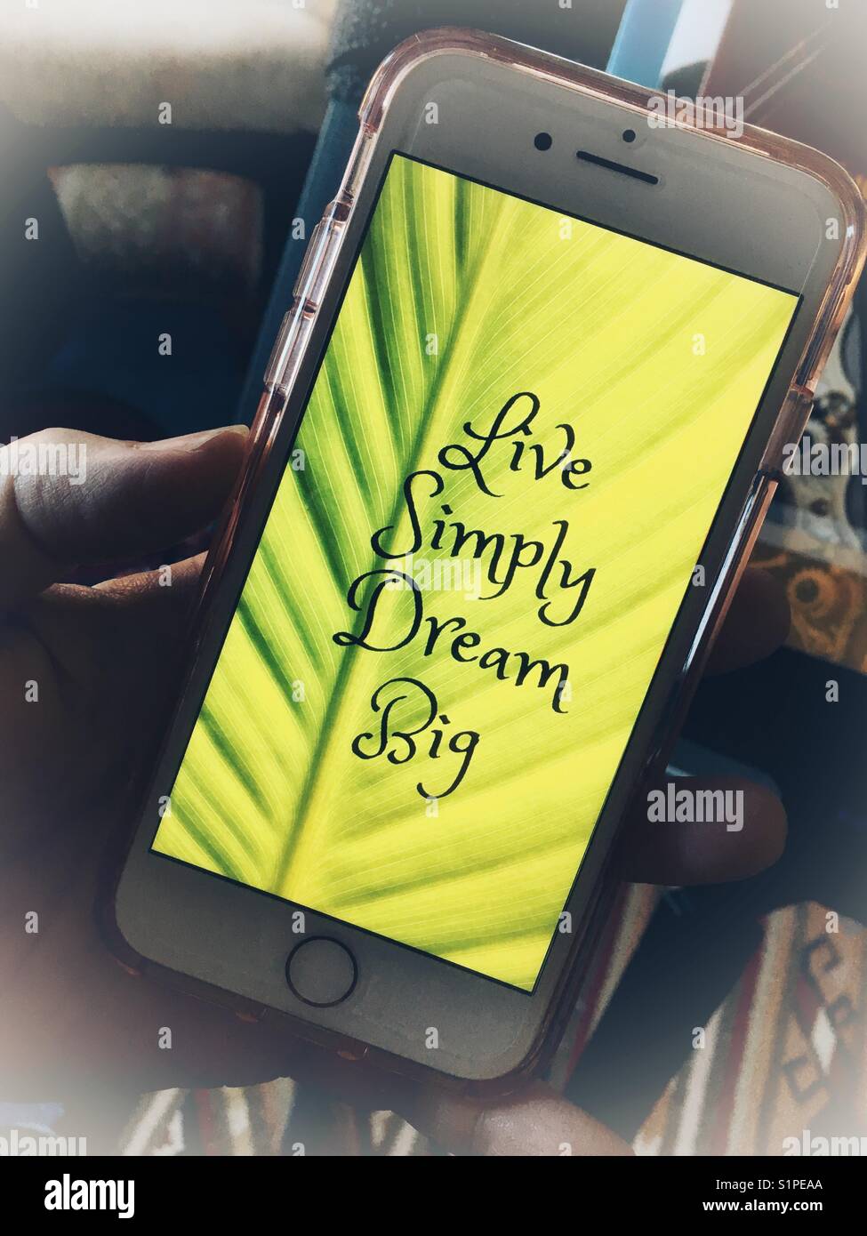 Inspirational mantra. iPhone in woman’s hand with “Live Simply, Dream Big” on the screen - Smartphone Captured Stock Image