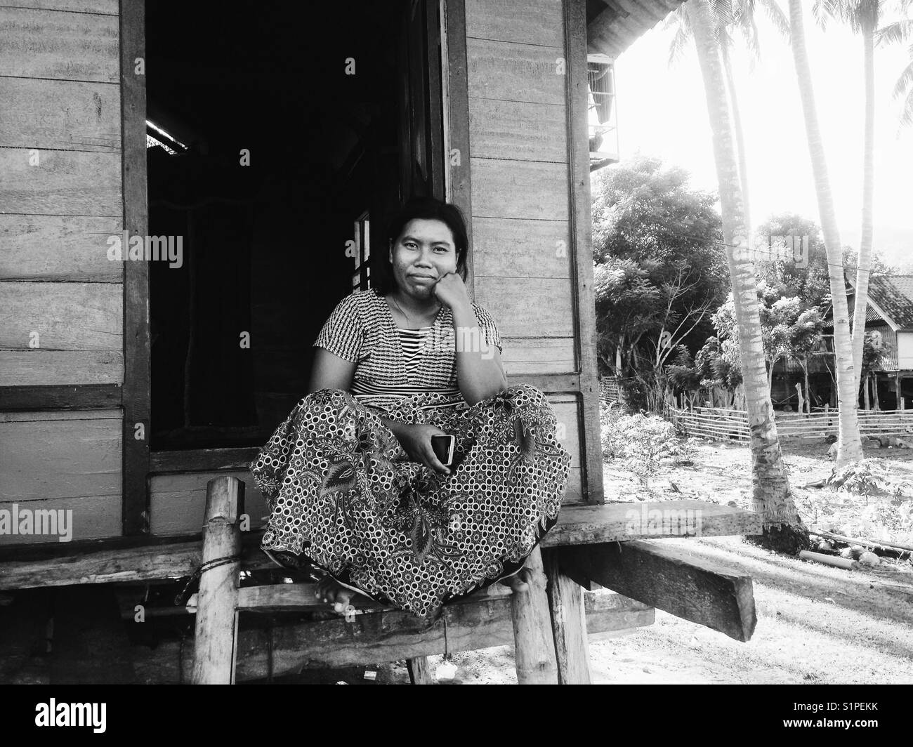 local indonesian woman sitting at her door Stock Photo