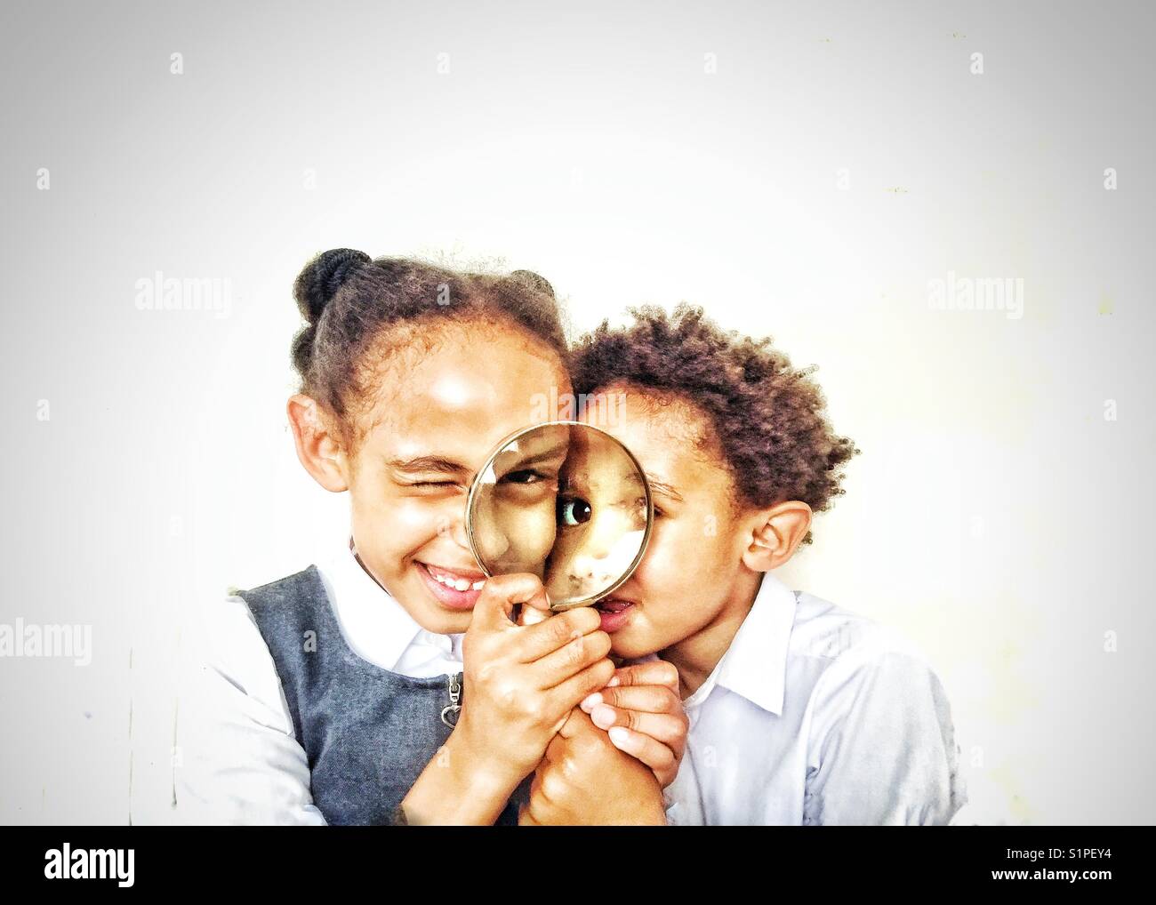 Two children peering through a magnifying glass. - Smartphone Captured Stock Image