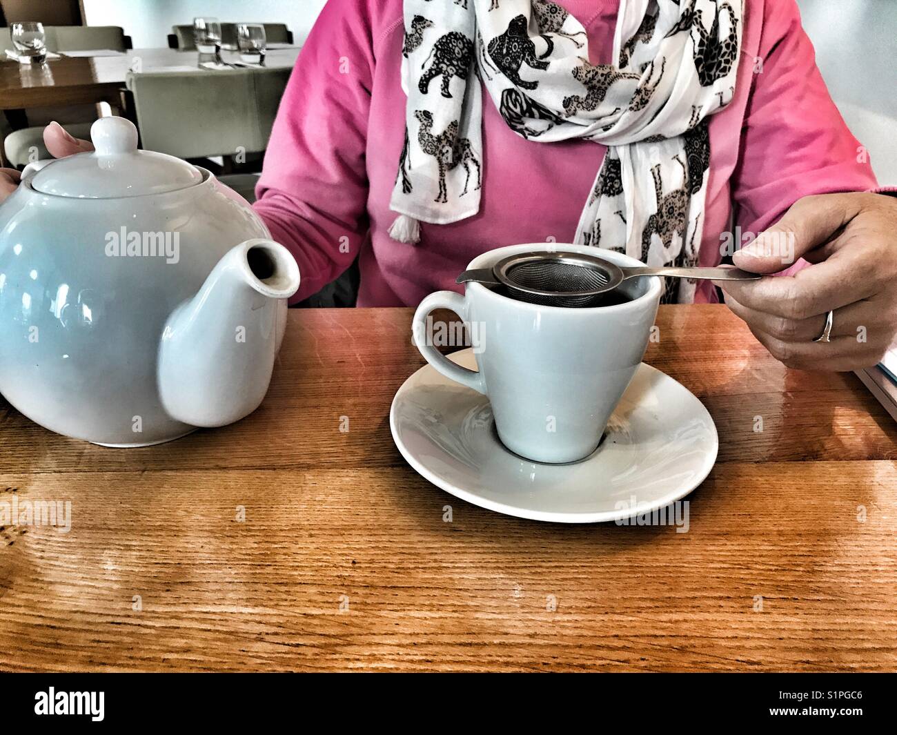 Woman in a restaurant, pouring a cup of tea from a teapot - Smartphone Captured Stock Image