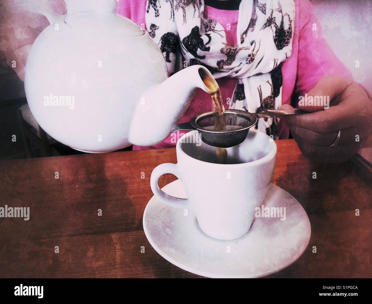 Woman in a restaurant, pouring a cup of tea from a teapot - Smartphone Captured Stock Image