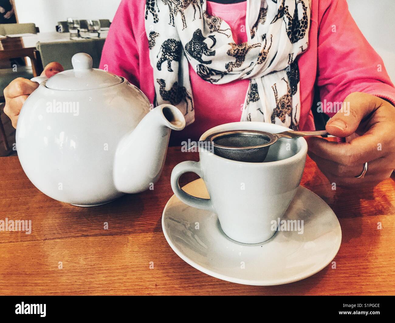 Woman in a restaurant, pouring a cup of tea from a teapot - Smartphone Captured Stock Image