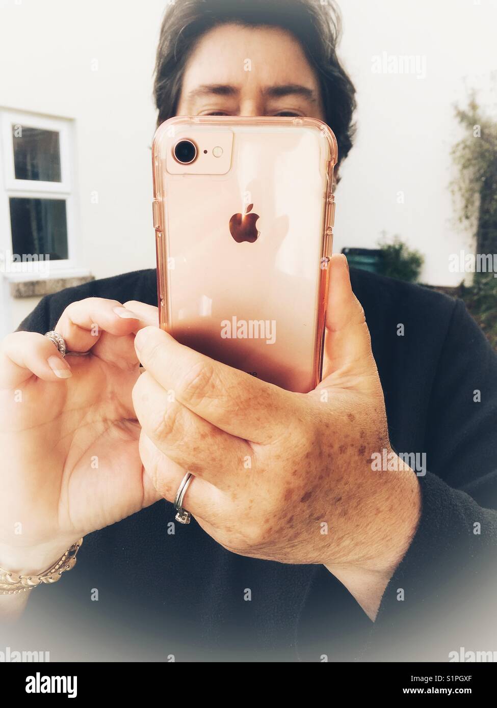 Low angle view, woman using iPhone outdoors - Smartphone Captured Stock Image