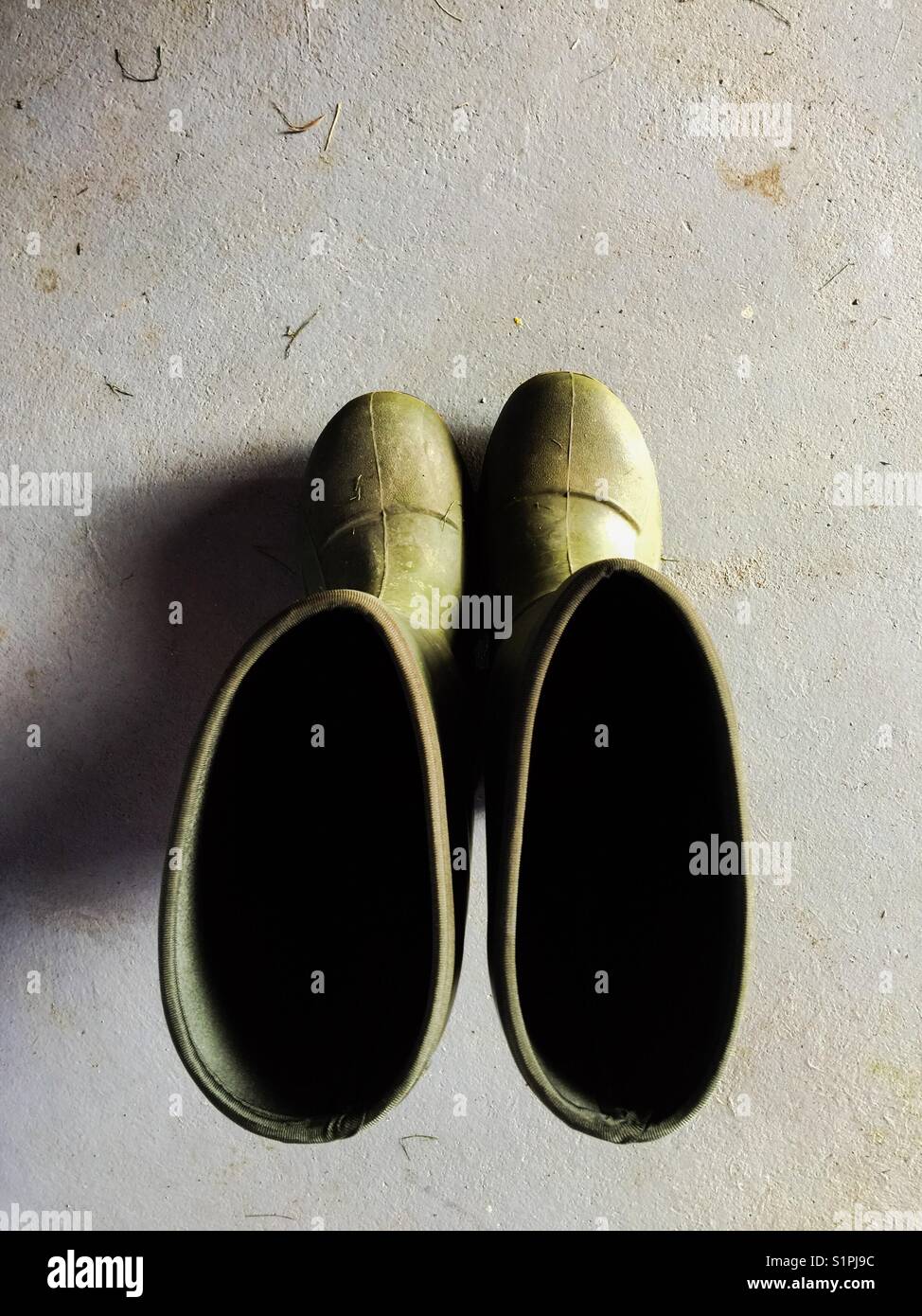 Dirty, green work boots shot from above on concrete floor - Smartphone Captured Stock Image