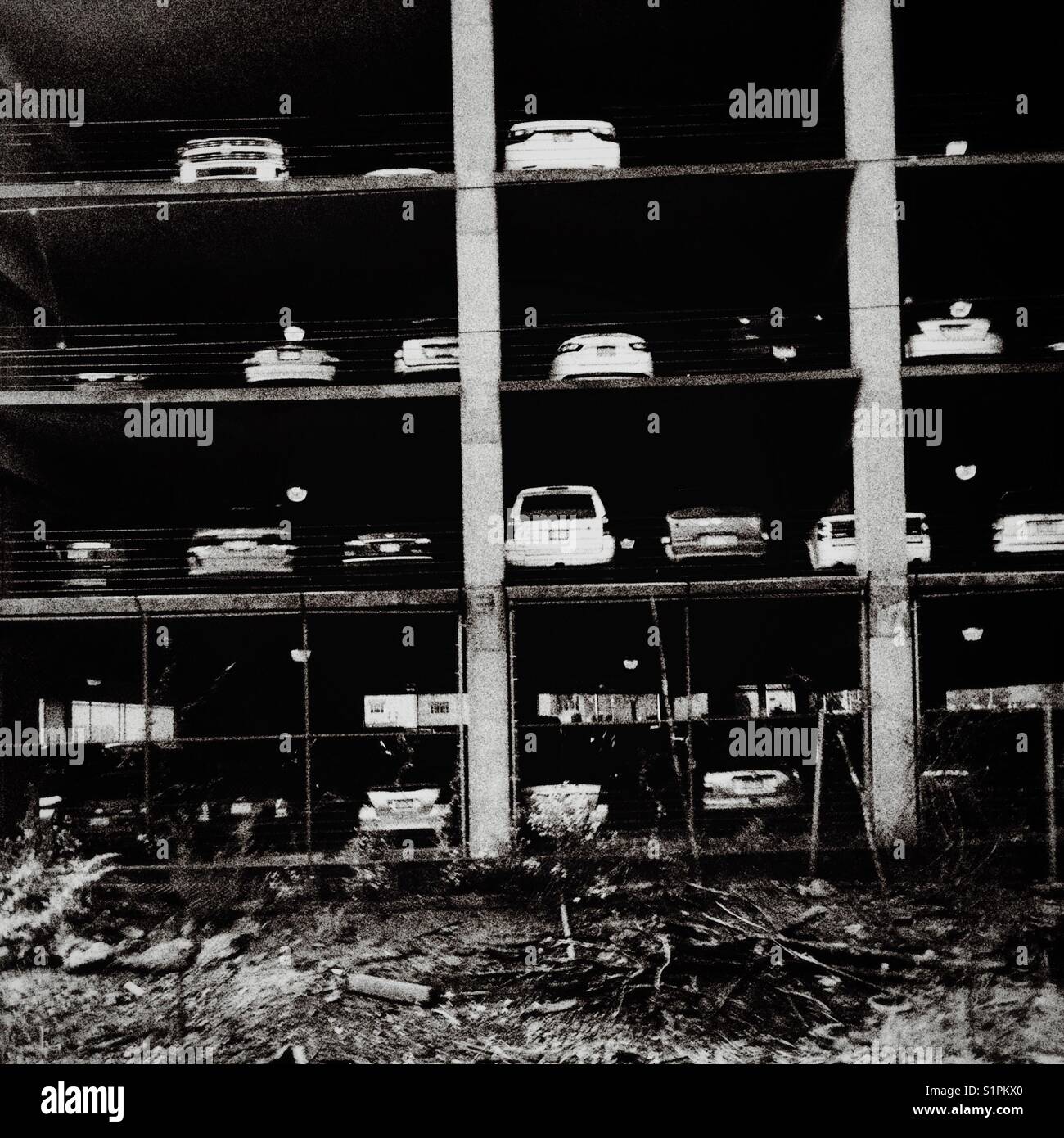 A black and white image of cars on multiple levels of a parking garage Stock Photo