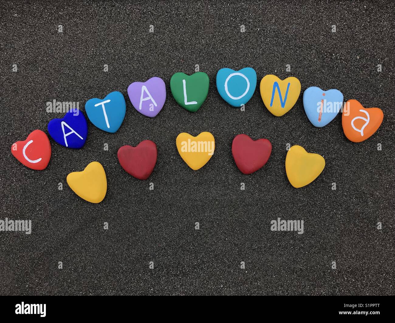 Catalonia, souvenir with colored heart stones over black volcanic sand - Smartphone Captured Stock Image Catalonia, souvenir with colored heart stones over black volcanic sand - Smartphone Captured Stock Image