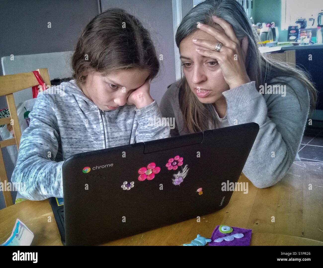 Mother helping daughter with homework on laptop computer. - Smartphone Captured Stock Image