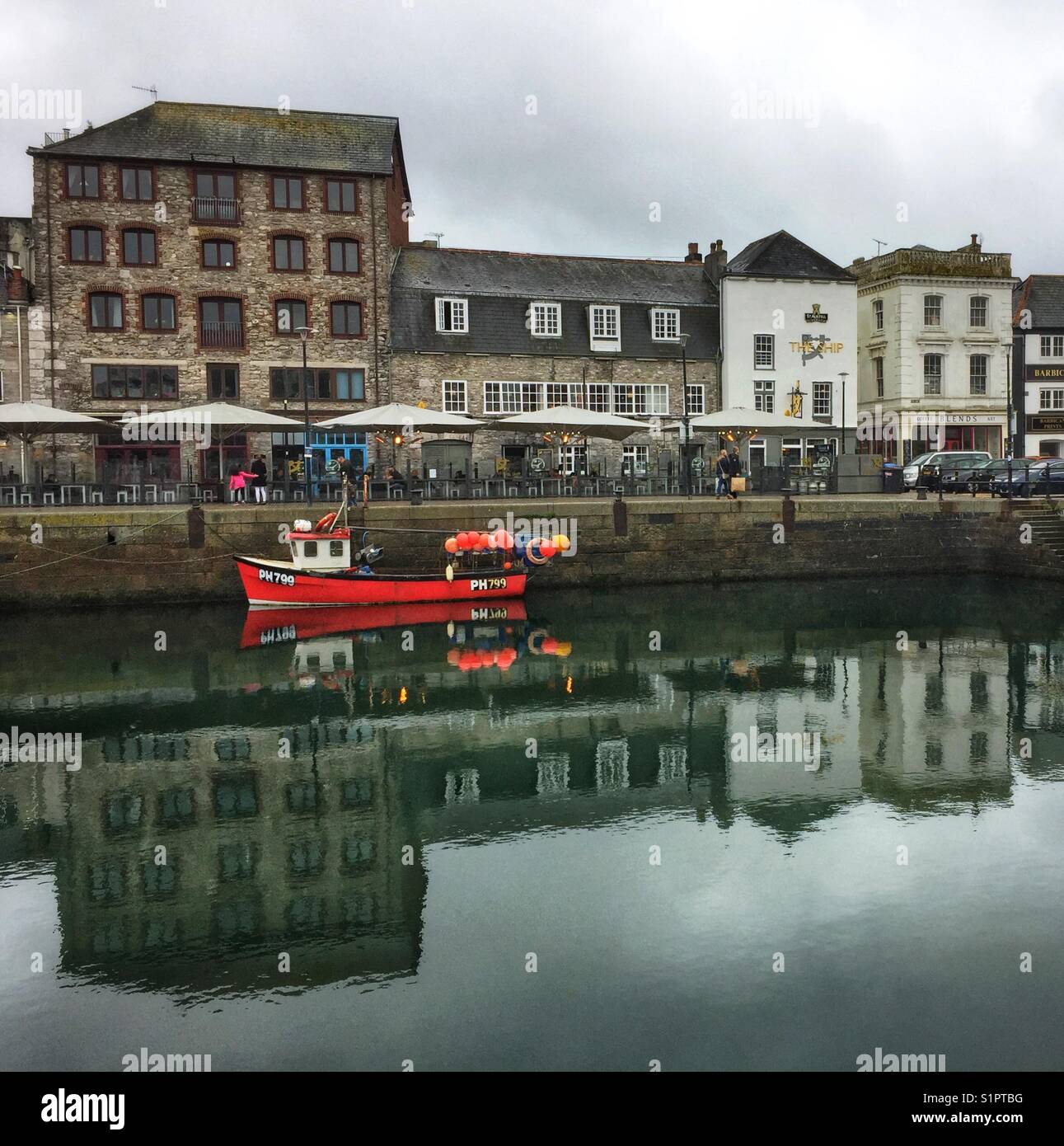 THE BARBICAN, PLYMOUTH. 7th October 2017. A red working fishing boat moored in front of busy restaurants. Stock Photo