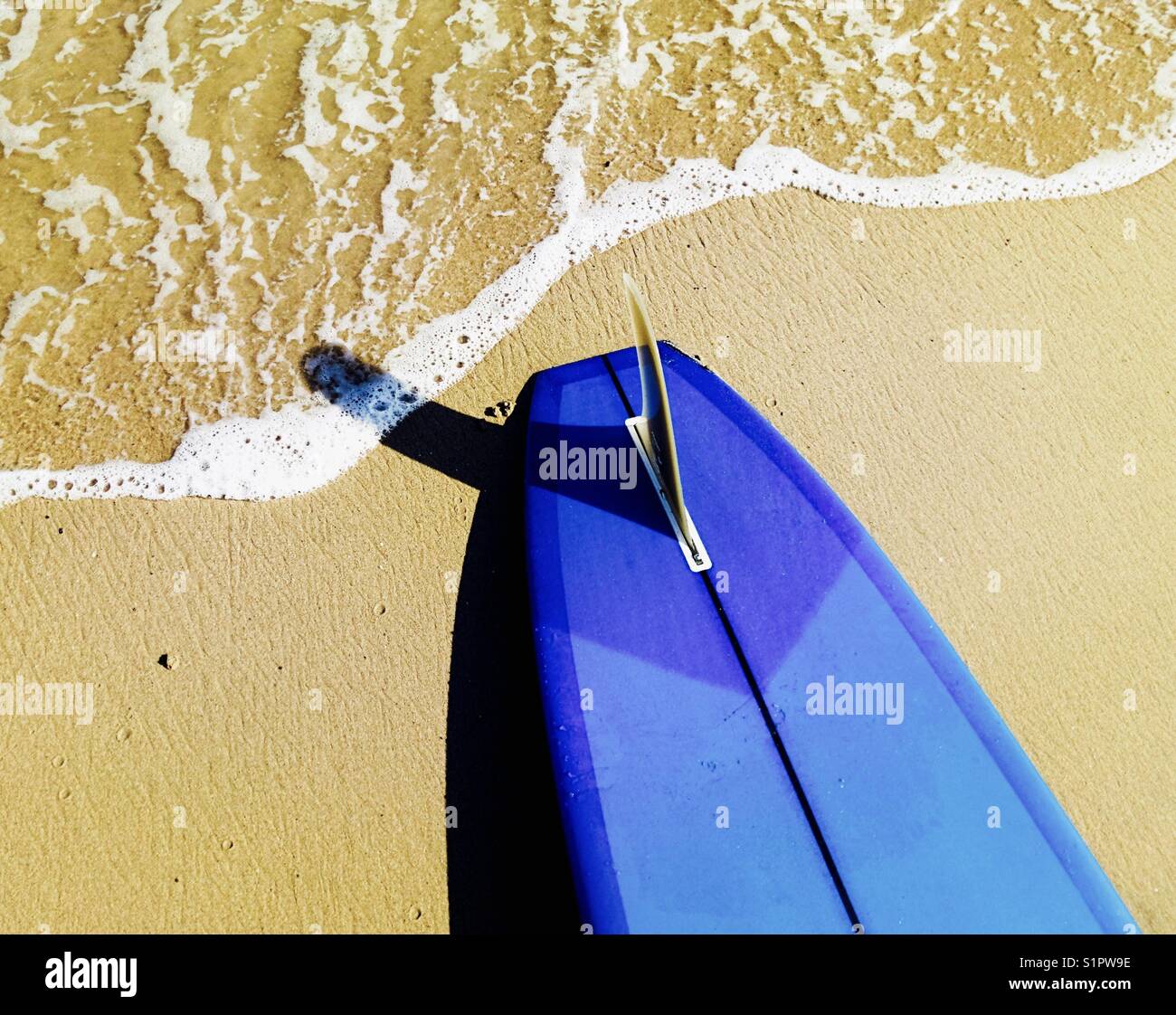 A surfboard at the waters edge at the beach. Malibu, California USA