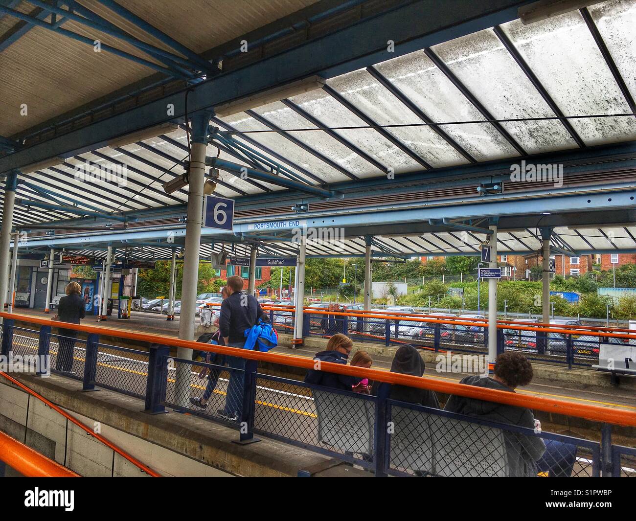 Guildford Train station, passengers on platform  and commuter’s cars parked beyond Stock Photo