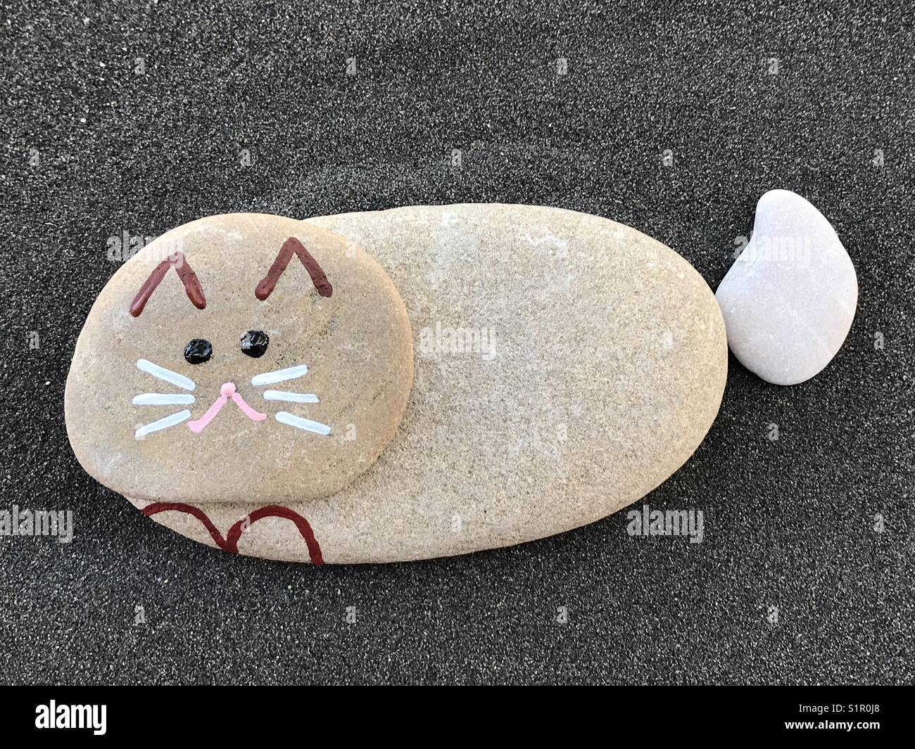 My sweet stone cat over black volcanic sand - Smartphone Captured Stock Image