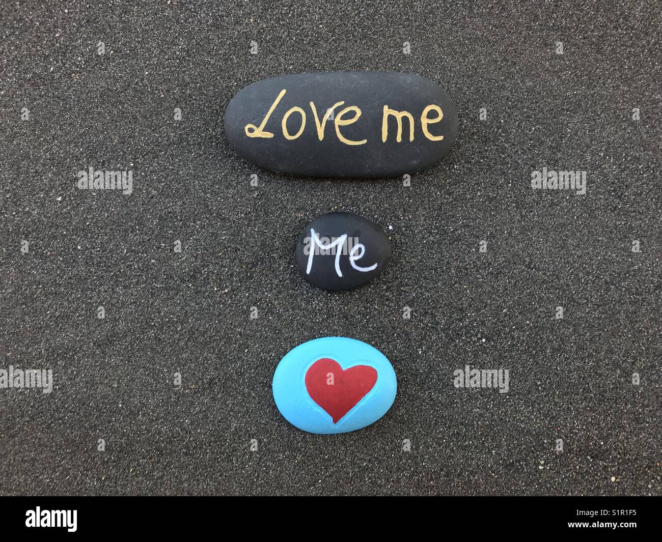 Love me message carved on stones over black volcanic sand Stock Photo