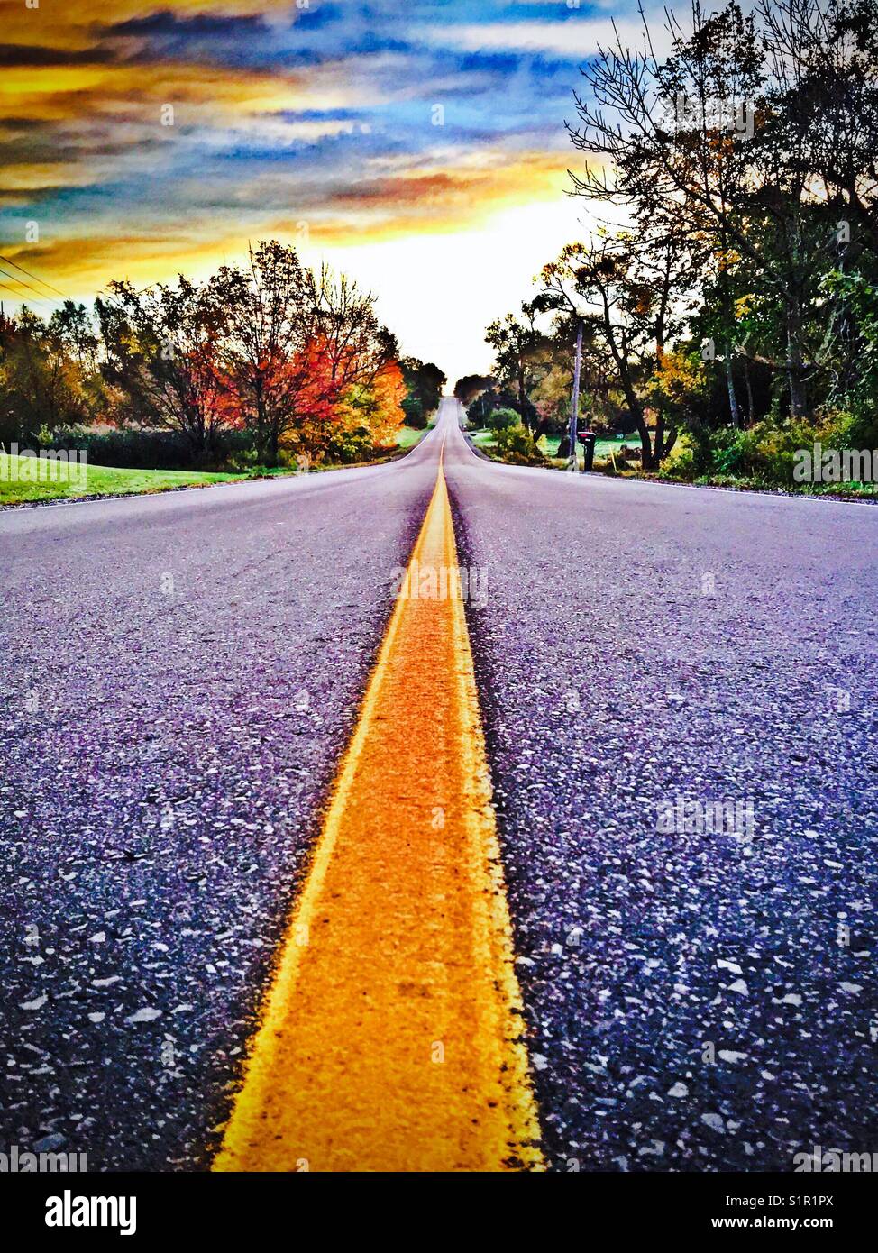 View from middle of road at sunrise in rural Southern Ontario, Canada in autumn - Smartphone Captured Stock Image