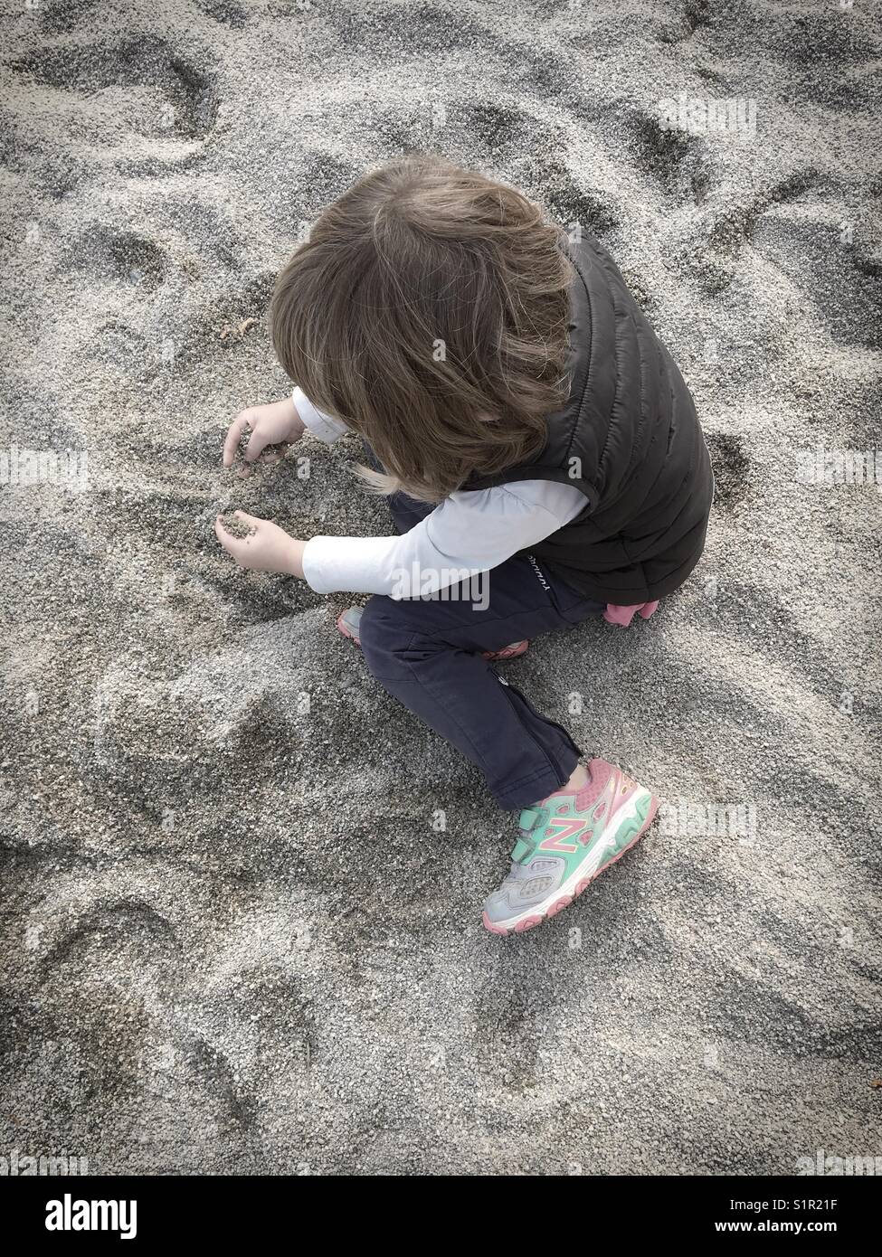 Young girl playing alone in a sandpit. Stock Photo