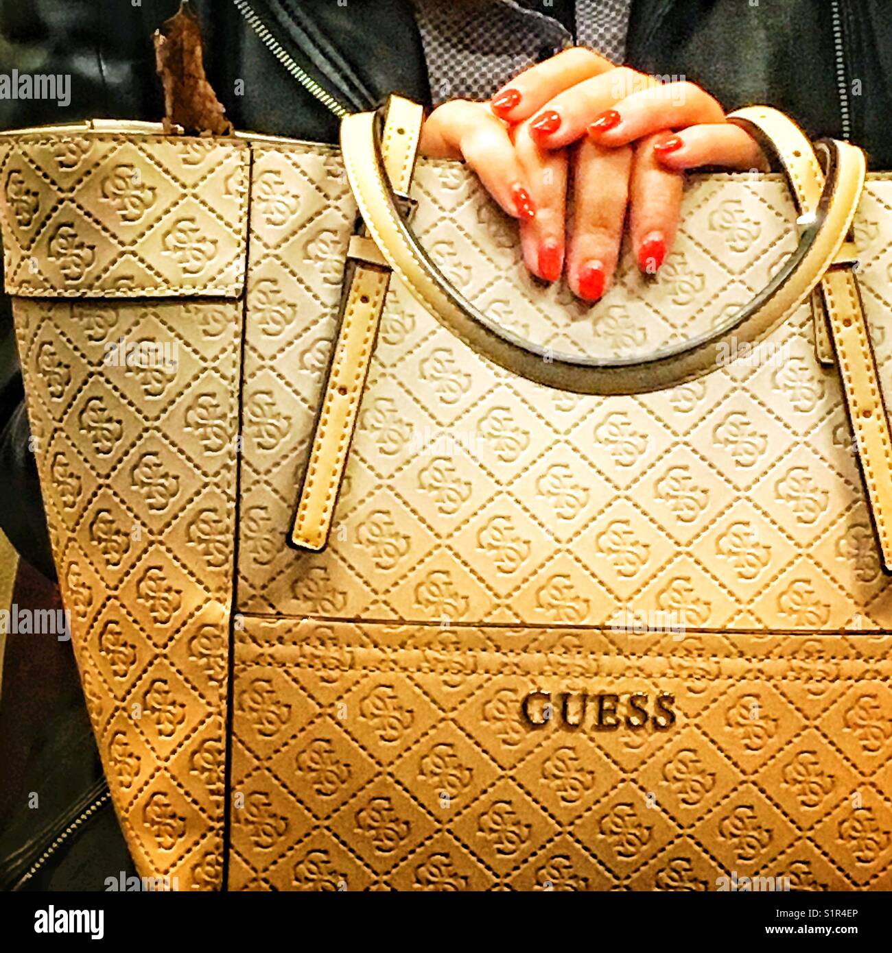 Woman hands on a GUESS handbag, a luxury brand, a handbag by GUESS - Smartphone Captured Stock Image