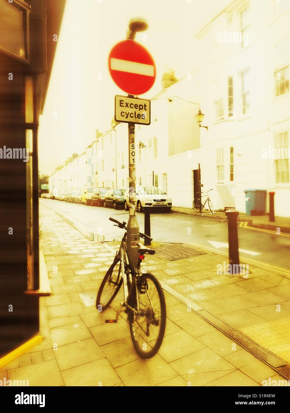 Bicycle parked against No Entry sign with contradictory notice, ‘except cycles’. Stock Photo