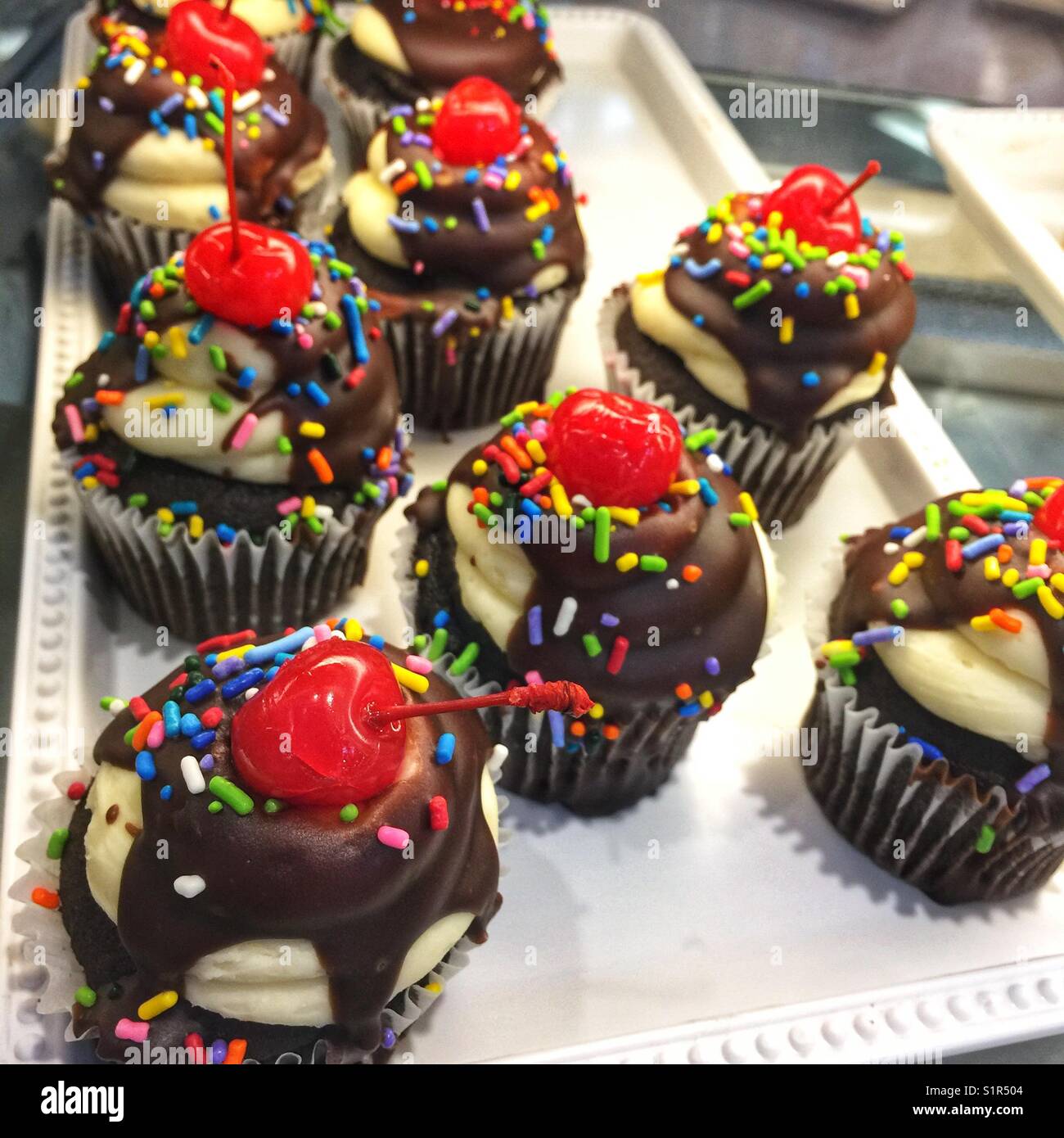 Colorful cupcakes topped with chocolate icing, sprinkles and a cherry - Smartphone Captured Stock Image
