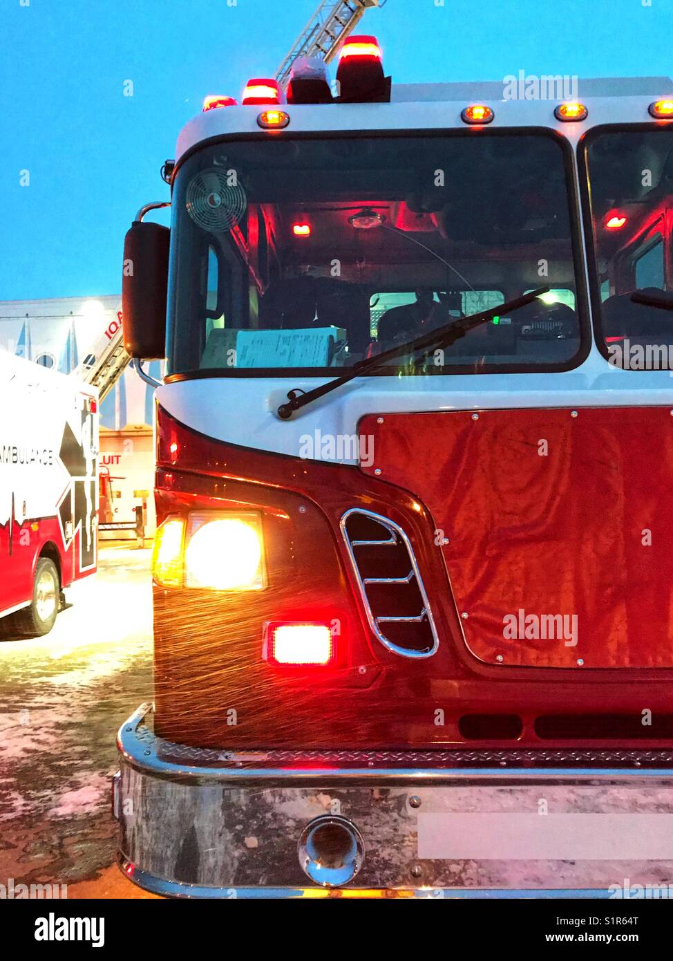 Fire truck and ambulance parked in blowing snow, Iqaluit, Canada Stock Photo