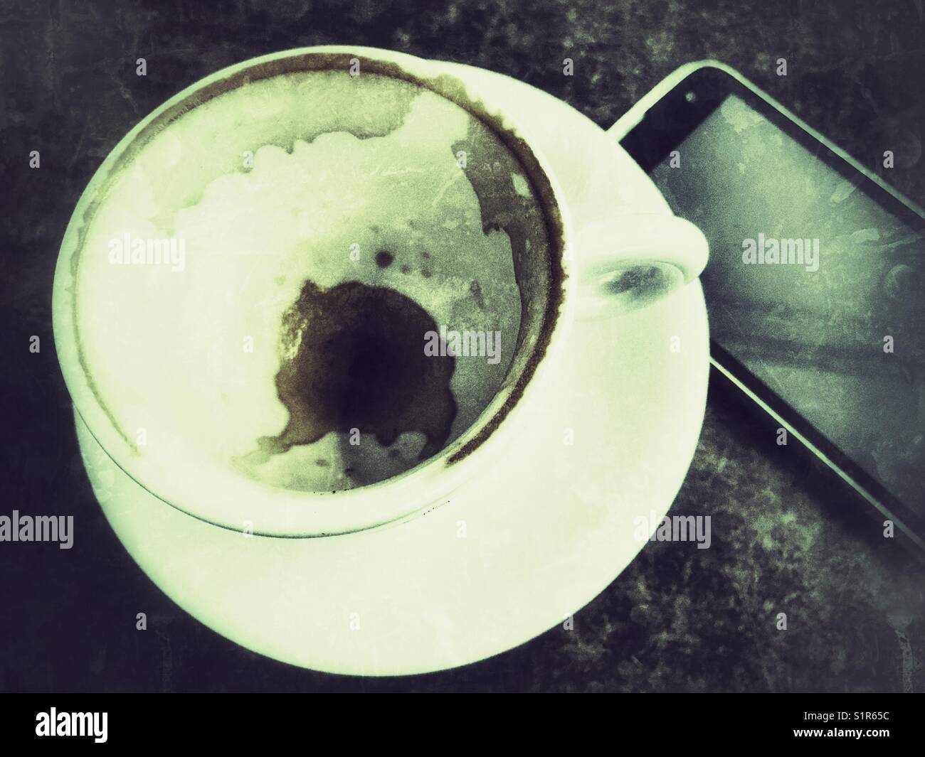 Empty coffee cup and mobile phone on a table - Smartphone Captured Stock Image