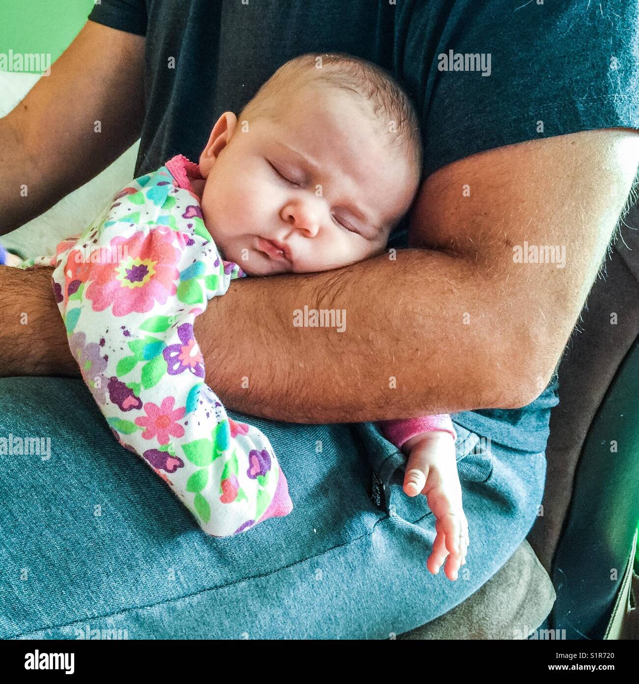 Infant girl asleep on father' arm Stock Photo
