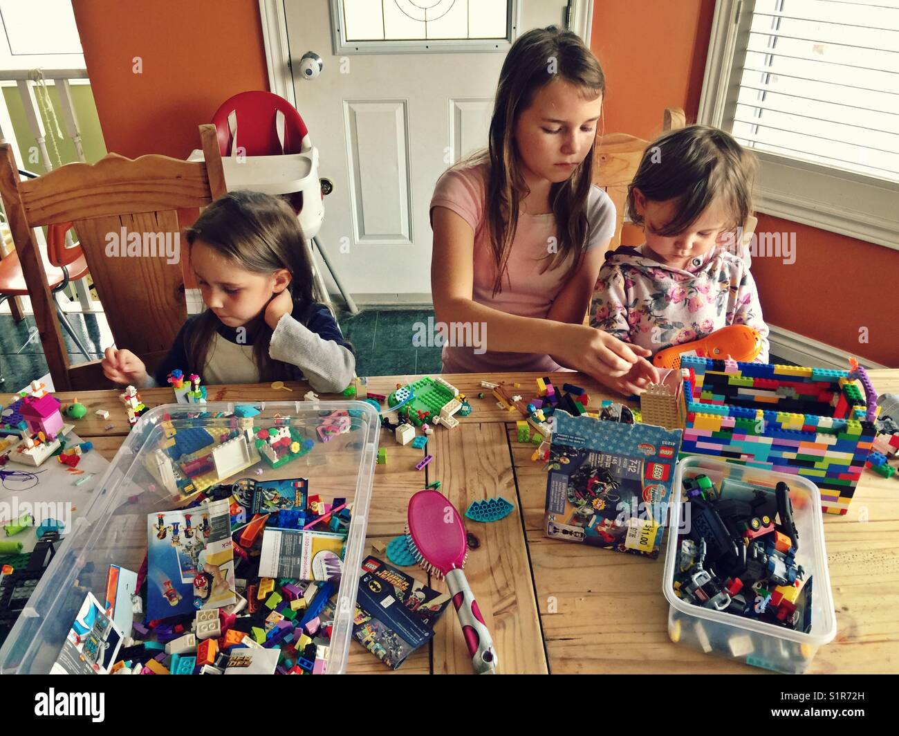 Three sisters playing Lego on kitchen table - Smartphone Captured Stock Image