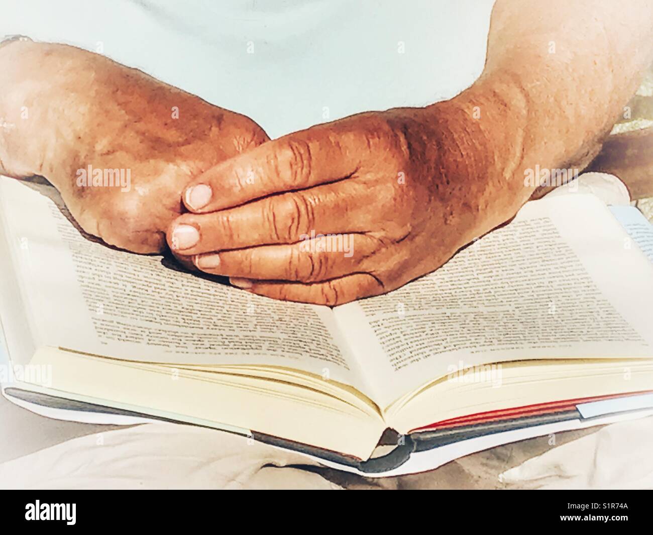Man reading a book outdoors, midsection close-up of hands and book - Smartphone Captured Stock Image