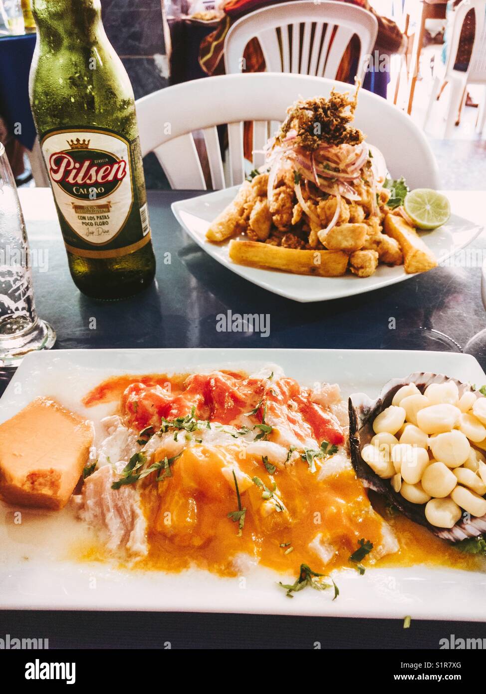 Rocoto and ají Tiradito served with corn and sweet potato, and Dish Jalea, Peruvian version of Fish and ships. Pilsen Callao peruvian Pilsner beer. At El Muelle de Barranco Restaurant in Lima PERU - Smartphone Captured Stock Image