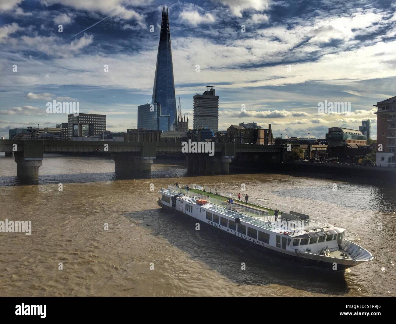A boat travels up the river Thames and the Shard is seen in the  London skyline - Smartphone Captured Stock Image