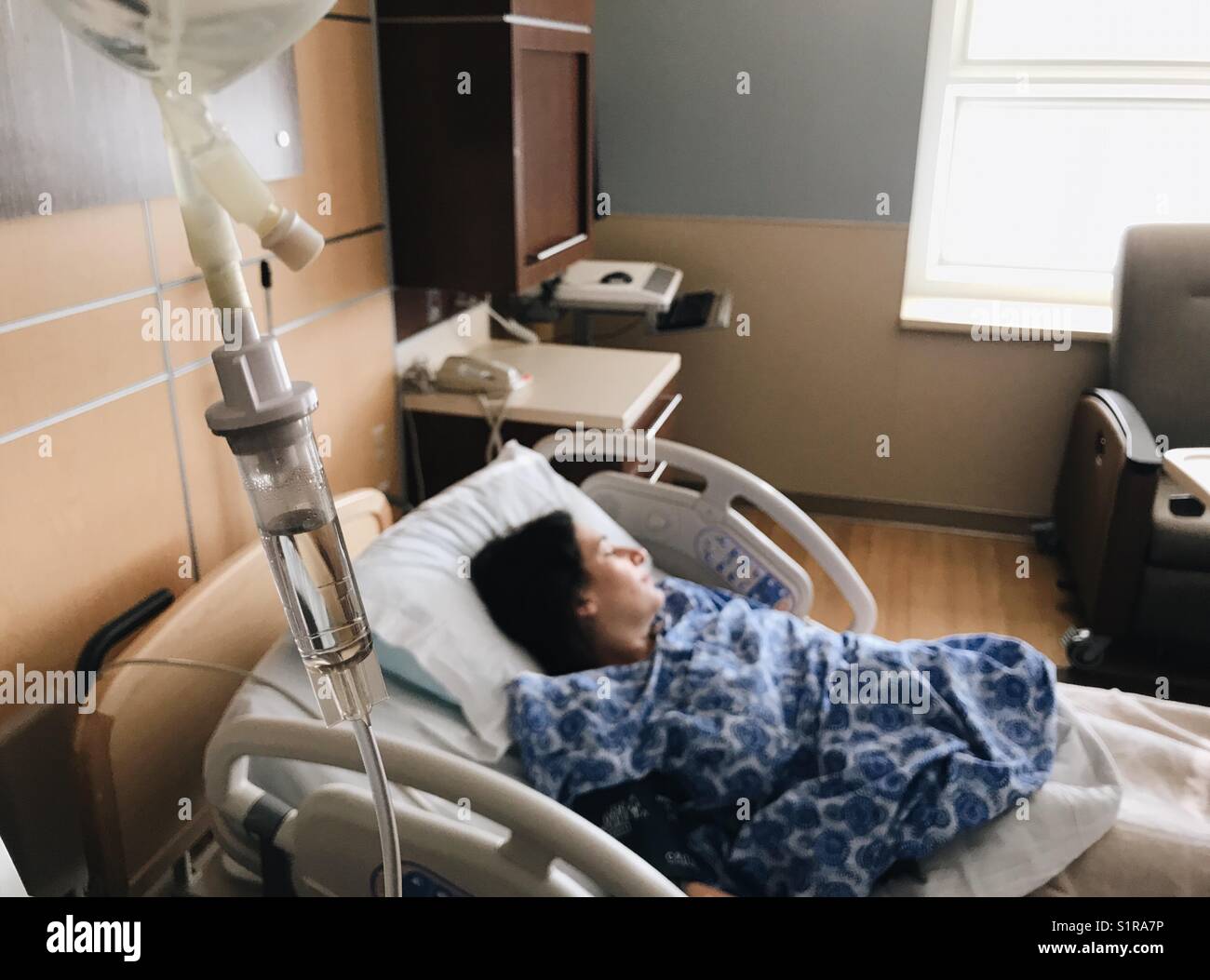 A pregnant woman on a hospital bed connected to an intravenous drip. Stock Photo