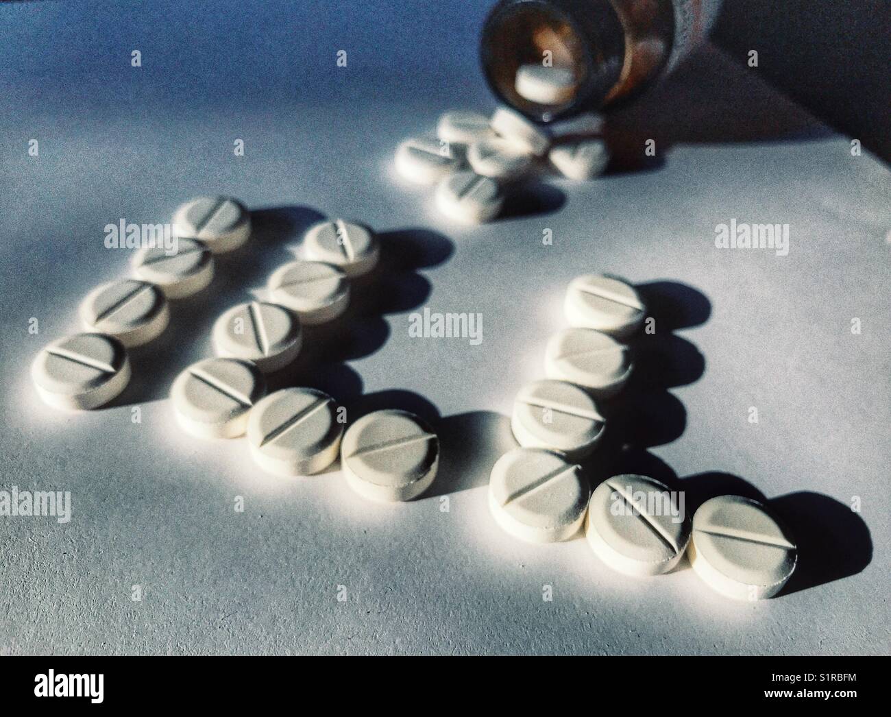 Healthcare and medicine. Pills spilling out of a bottle behind the word ILL - Smartphone Captured Stock Image