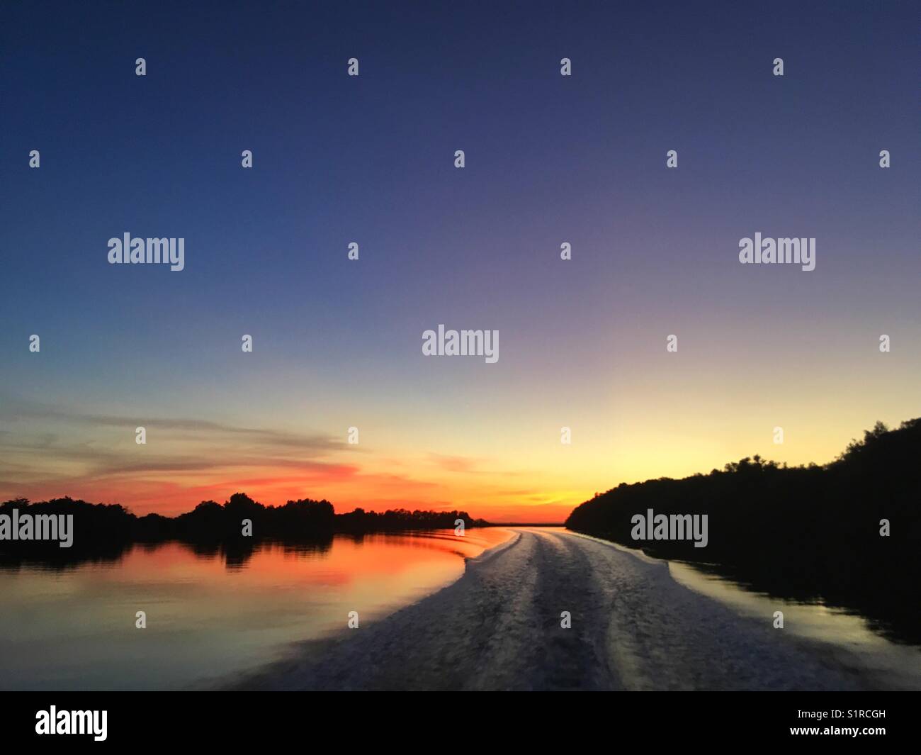 Boat wake at sunrise on the Adelaide River in the Northern Territory of Australia. Stock Photo