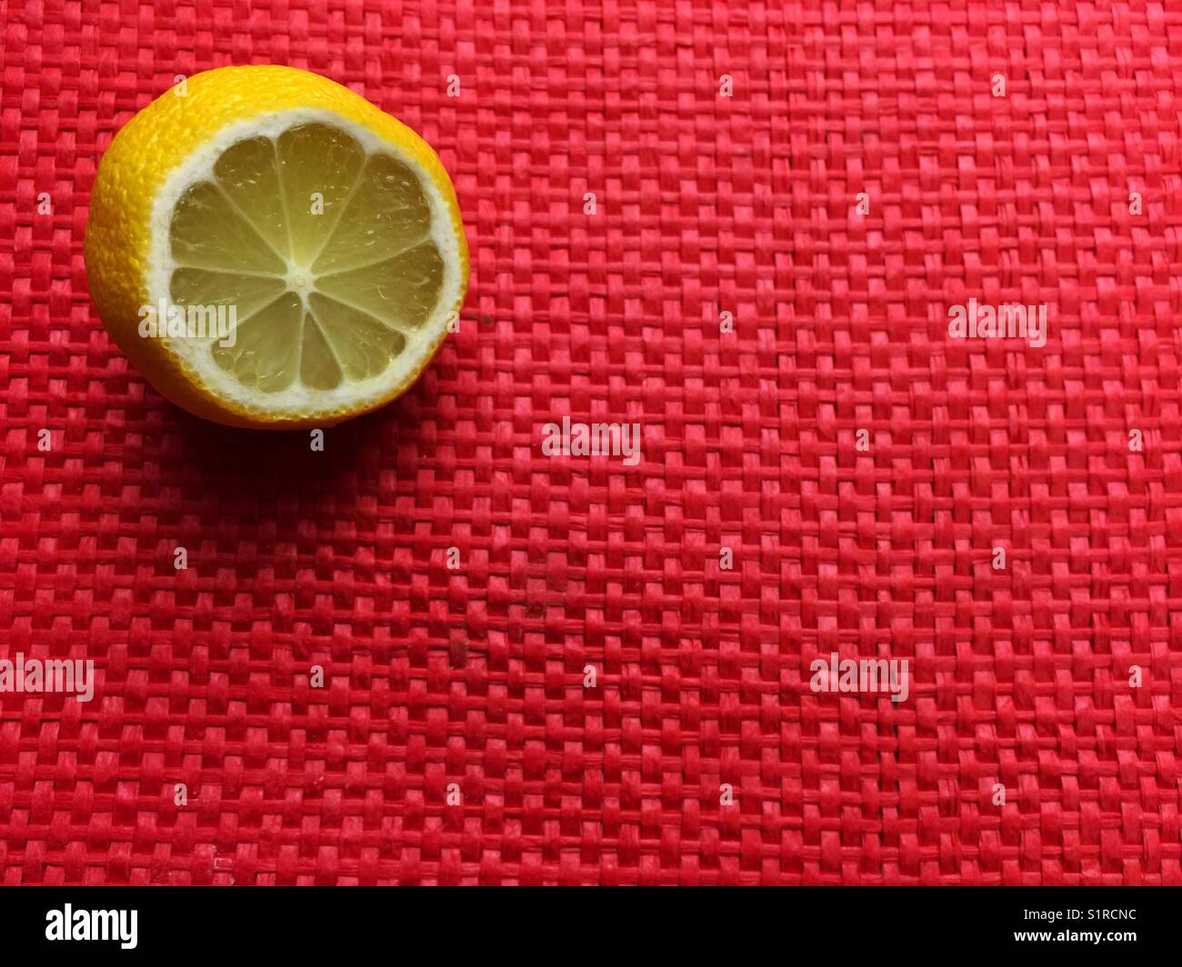 Cut lemon on red woven place mat Stock Photo