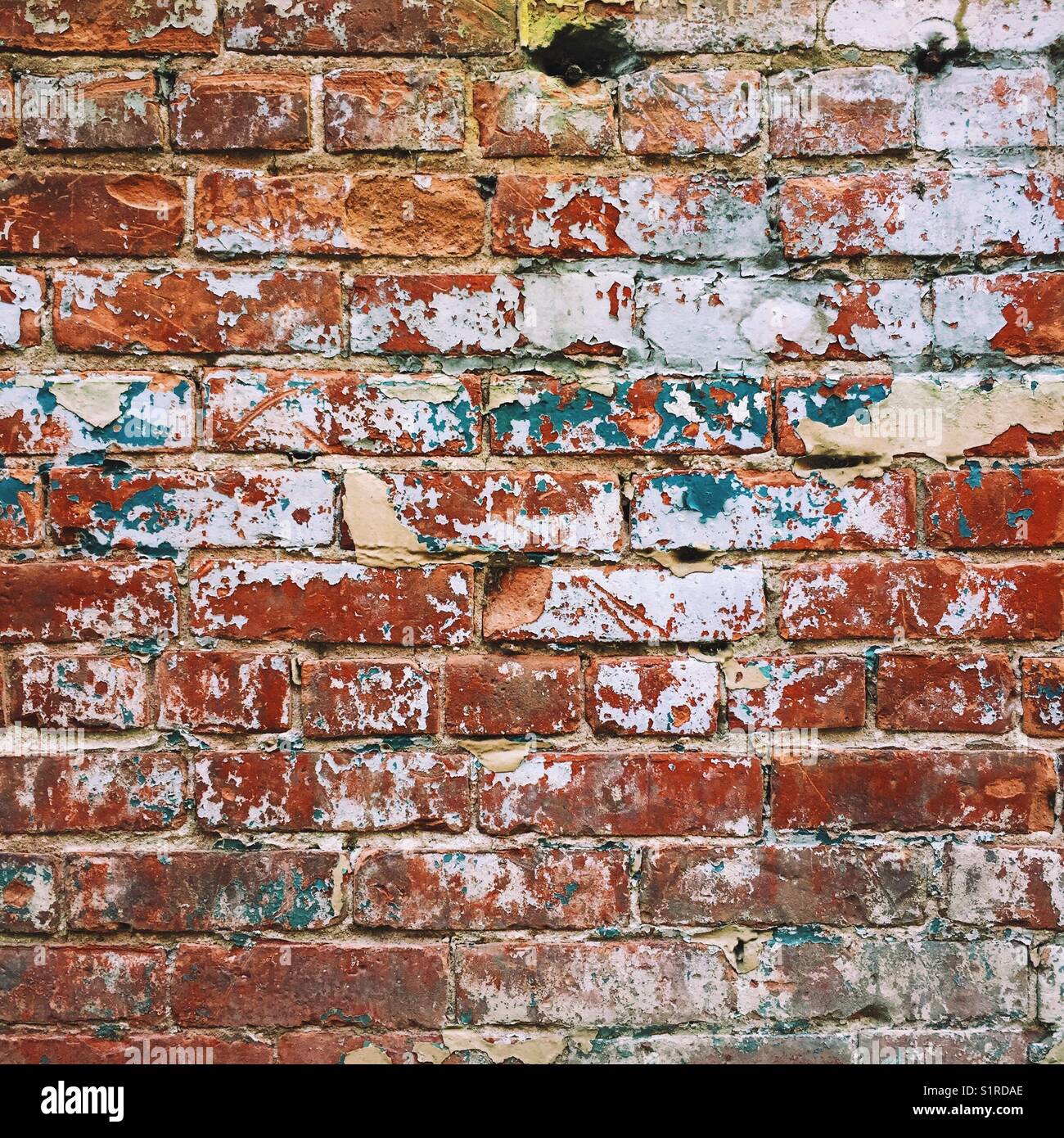 An old damaged brick wall with peeling paint Stock Photo