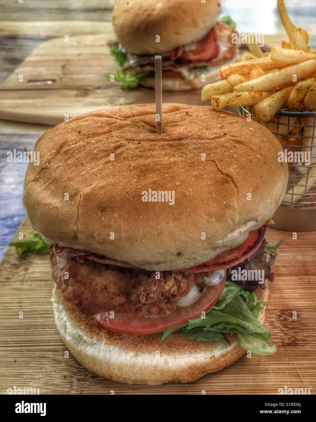 Two juicy fried chicken hamburgers and chips in Australia. Know elsewhere as fried chicken sandwiches and fries Stock Photo