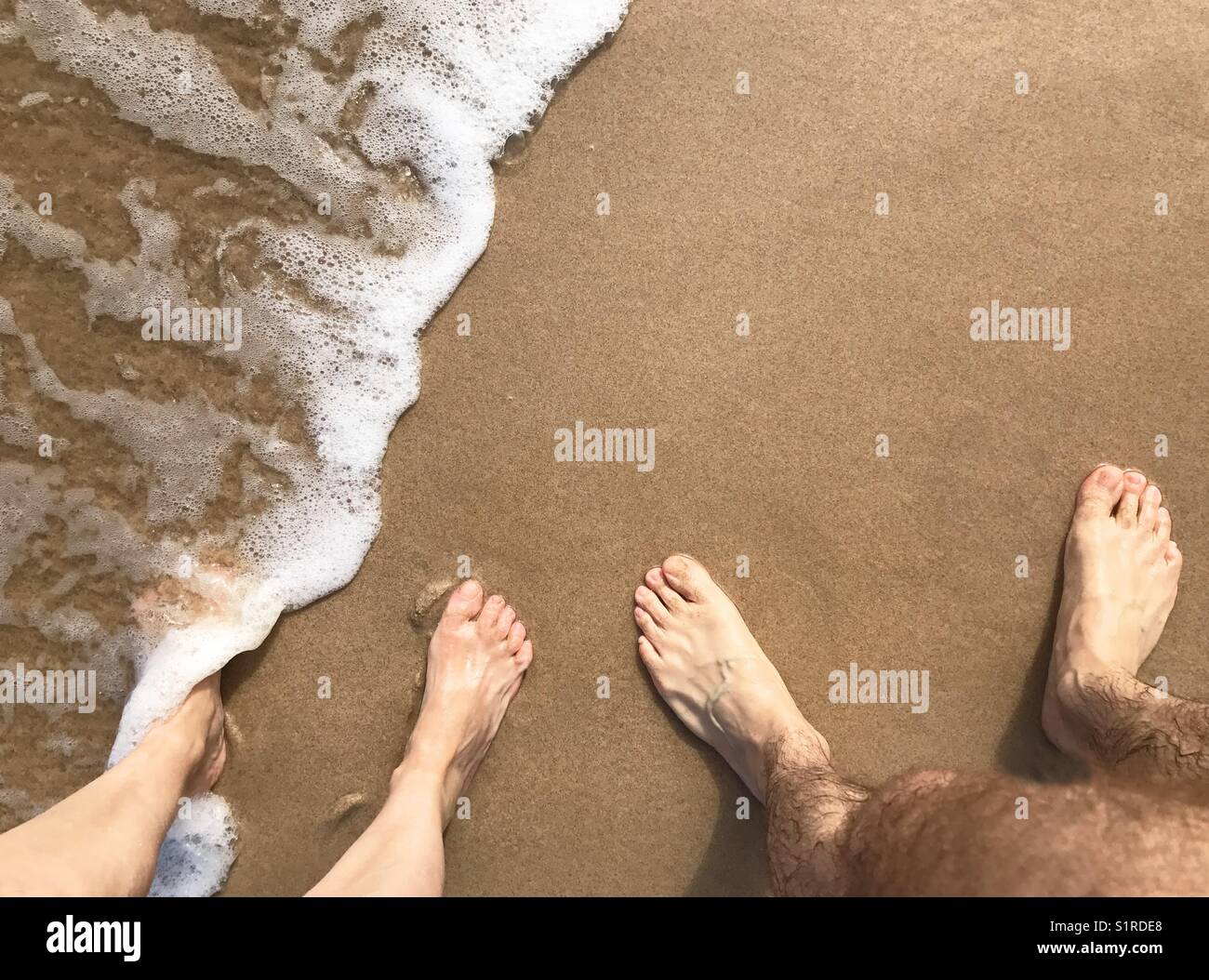 Man and woman' feet at the sea shore. - Smartphone Captured Stock Image