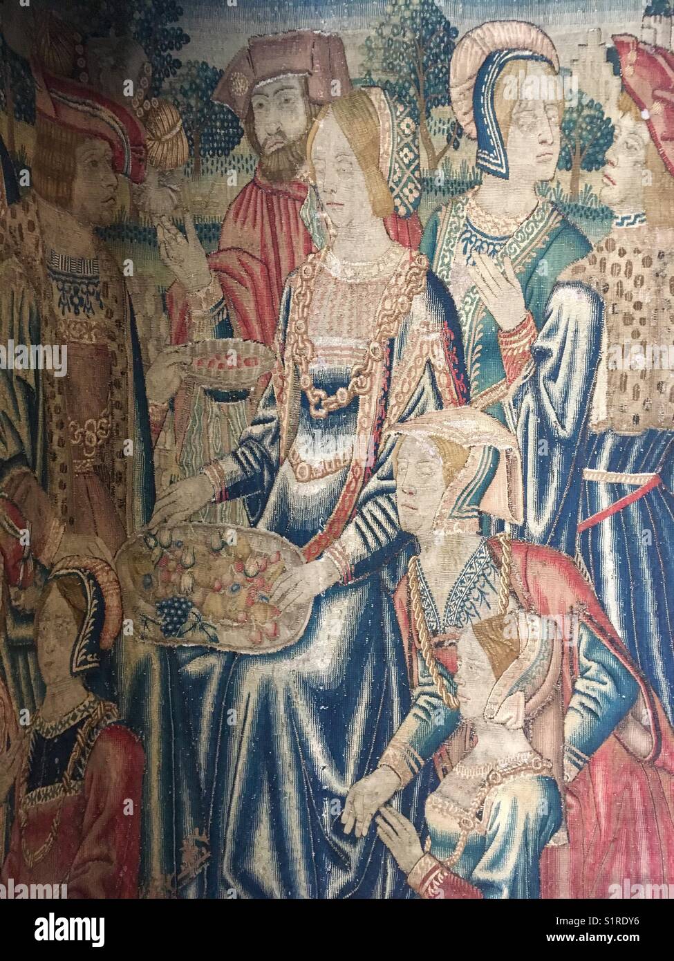 Flemish 15th Century Tapestry depicting a jolly gathering of well-dressed men and women sharing a large plate of fruit Stock Photo