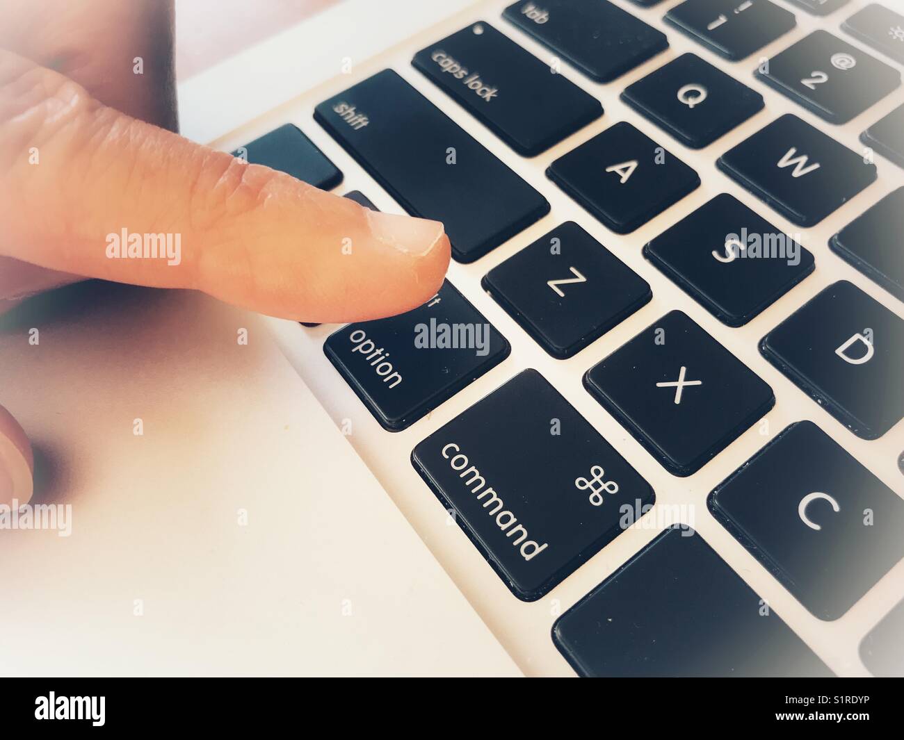 Finger above the option key on a laptop computer keyboard stock photo