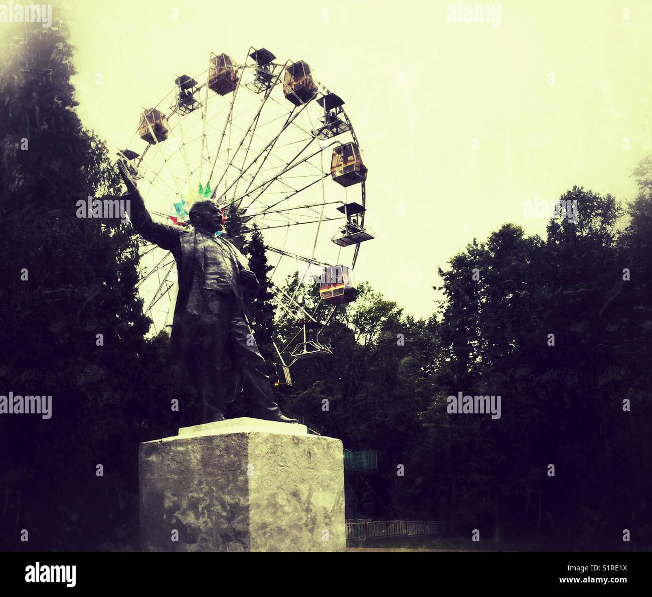 Grunge moody image of Statue of Lenin against ferris wheel in The park in Krasnogorsk, Moscow region, Russia - Smartphone Captured Stock Image