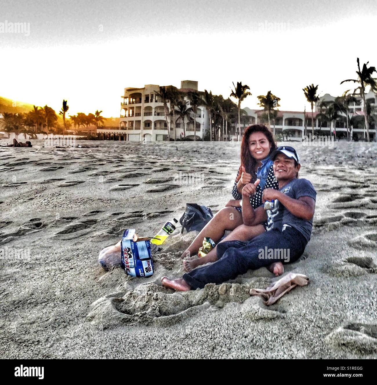 Happy couple sitting on the beach at dusk. - Smartphone Captured Stock Image